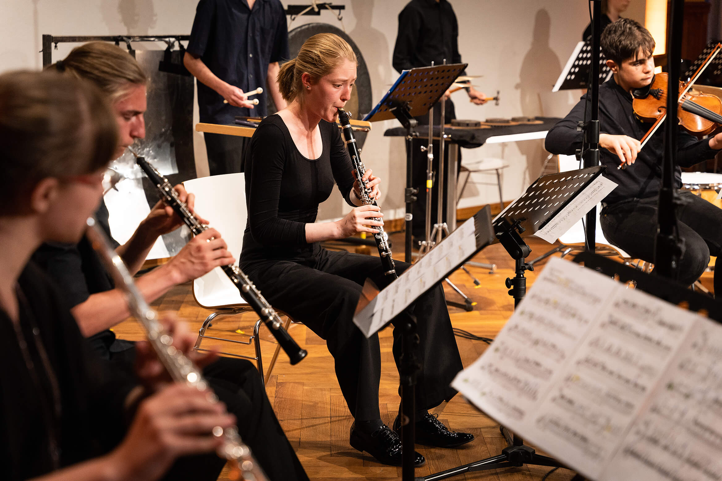 Das Bild zeigt eine konzentrierte Oboe Spielerin, neben anderen Musikerinnen die ebenfalls Oboa, Querflöte und Violine spielen