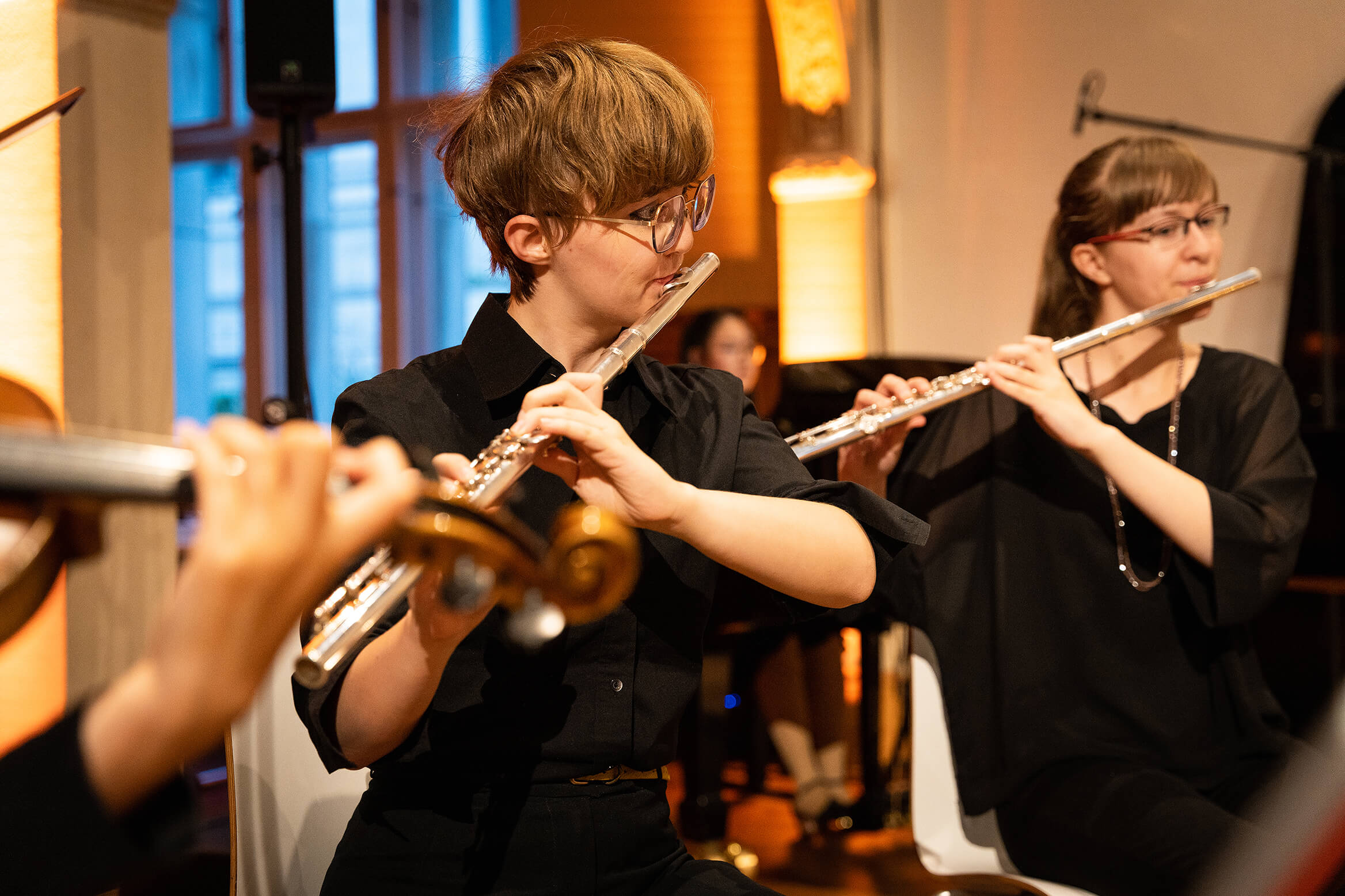 Das Bild zeigt zwei junge Musiker:innen während des Konzertes beim Querflöte spielen.